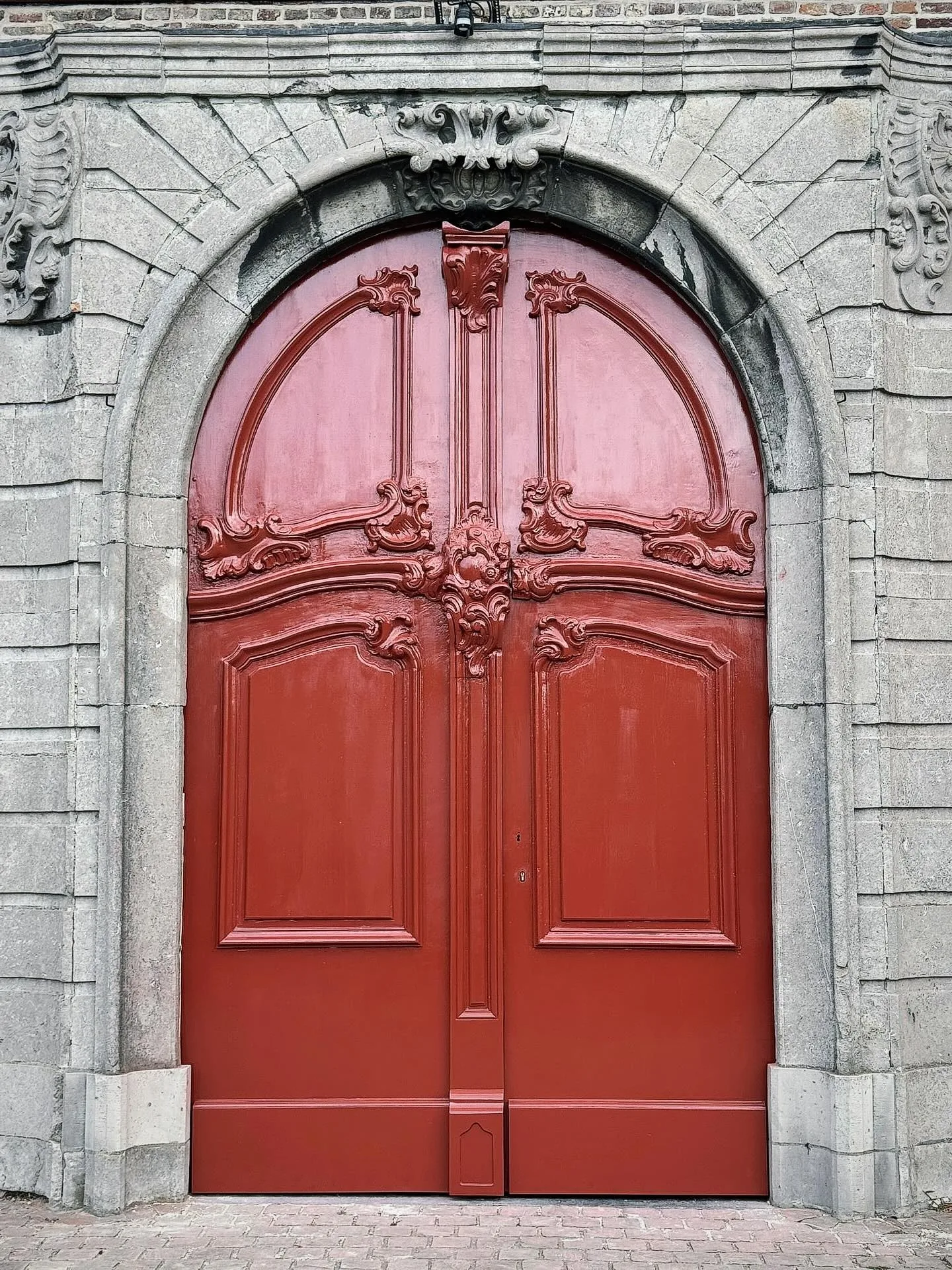 Gerestaureerde rode kerkdeur van de Sint-Eligiuskerk in Eine